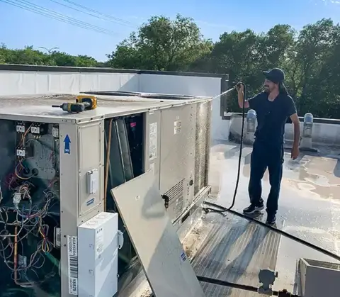 Cleaning the coils on a commercial HVAC unit.